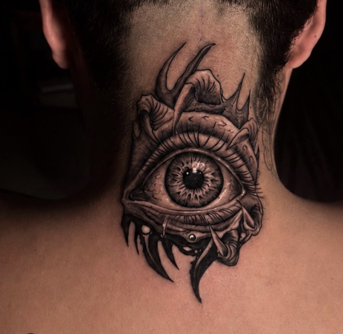 Large realistic eye appearing to tear through the skin on the back of a neck.