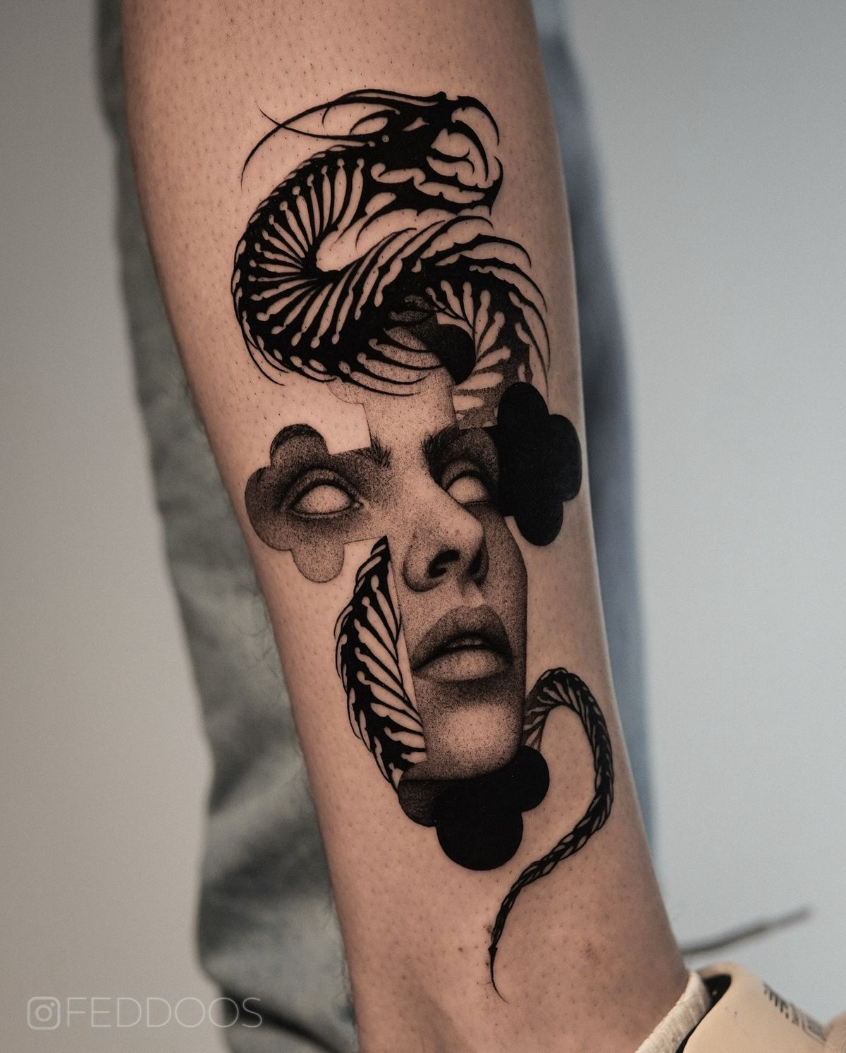 Black and grey surrealism piece combining a hollow-eyed portrait with a mechanical serpentine structure.